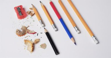 Kalemleri ve kalemtıraşı beyaz arka planda yavaş çekimde kapatın. Kırtasiye, öğrenim, okul ve eğitim kavramı.