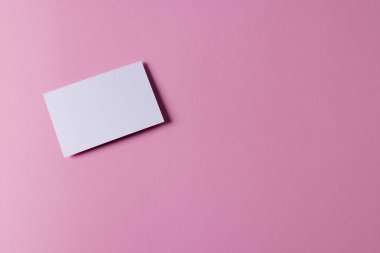 Pembe arka planda fotokopi alanı olan beyaz kartvizit. İş, kartvizit, kırtasiye ve yazma alanı kavramı.
