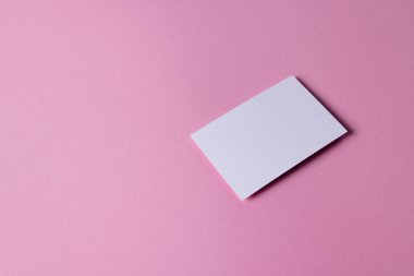 Pembe arka planda fotokopi alanı olan beyaz kartvizit. İş, kartvizit, kırtasiye ve yazma alanı kavramı.