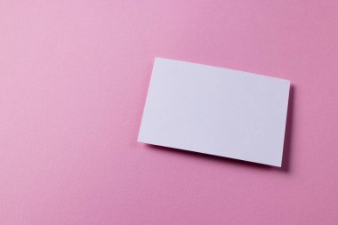 Pembe arka planda fotokopi alanı olan beyaz kartvizit. İş, kartvizit, kırtasiye ve yazma alanı kavramı.