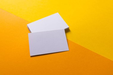 Sarı ve turuncu arka planda fotokopi alanı olan beyaz kartvizitler. İş, kartvizit, kırtasiye ve yazma alanı kavramı.