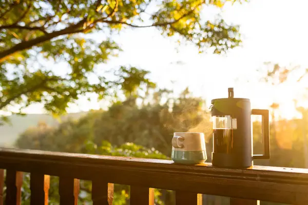 Balcony of log cabin with coffee press and coffee mug on sunny day. Nature, agriculture, summer, tranquillity and drink.