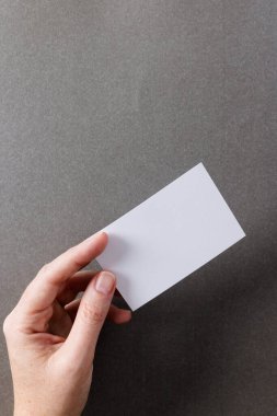 Gri arkaplanda fotokopi alanı olan beyaz bir kadının dikey görüntüsü. İş, kartvizit, kırtasiye ve yazma alanı kavramı.