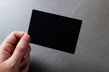 Beyaz bir kadının elinde siyah bir kartvizit tutarken, arka planda fotokopi alanı vardı. İş, kartvizit, kırtasiye ve yazma alanı kavramı.