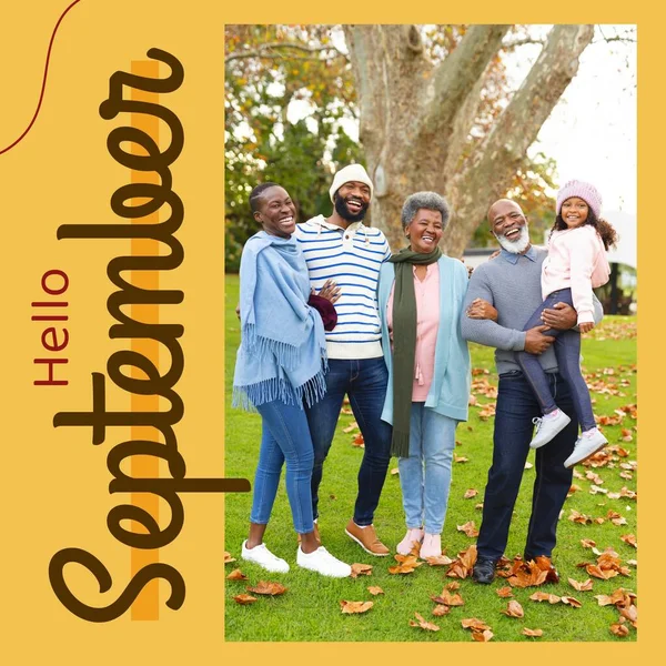 Hello september text in brown on yellow over happy three generation african american family in park. Celebration of nature and outdoor lifestyle in the first month of autumn digitally generated image.