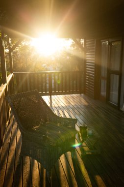 Güneşli bir günde kütük kabin balkon, koltuk ve kahve kupası dikey görüntü. Doğa, tarım, yaz, sükunet ve kırsal alan.