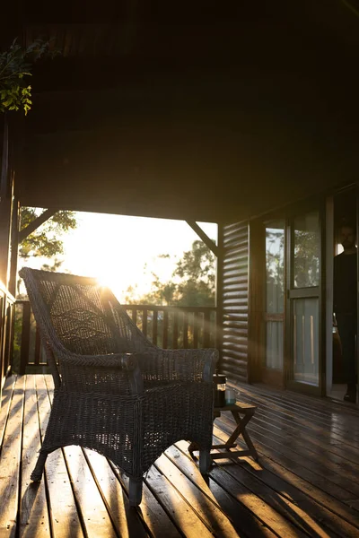 阳光明媚的日子里 带扶手椅和杯子咖啡的小木屋阳台的垂直图像 宁静和乡村景观 — 图库照片