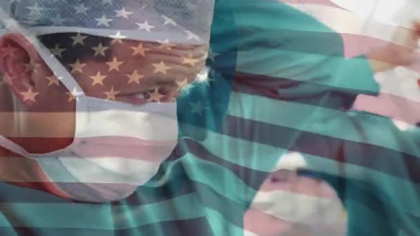 在医院里 在头戴外科口罩的高加索男性外科医生上空挥动美国国旗的动画 医疗和爱国主义概念 — 图库视频影像