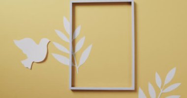 Çerçeveli ve yapraklı beyaz güvercini kapat ve sarı arkaplanda boşluğu kopyala. Barış ve savaş karşıtı hareket kavramı.