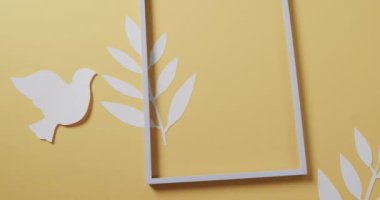 Çerçeveli ve yapraklı beyaz güvercini kapat ve sarı arkaplanda boşluğu kopyala. Barış ve savaş karşıtı hareket kavramı.