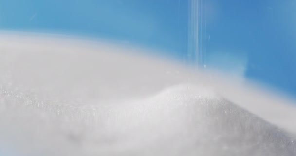 Kum Saatinin Yakın Çekim Videosu Mavi Arkaplan Üzerine Beyaz Kumlar — Stok video