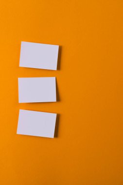 Beyaz kartvizitler ve turuncu arka planda fotokopi alanı. İş, kartvizit, kırtasiye ve yazma alanı dijital olarak oluşturulmuş görüntü.