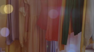 Moda mağazasında asılı duran kıyafetlerin üzerinde parlayan ışıkların animasyonu. Küresel moda, alışveriş, perakende satış, bağlantılar, konsept dijital olarak oluşturulmuş video.