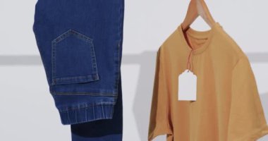 Askıda kot pantolon ve sarı tişört videosu ve beyaz arka planda kopya alanı. Moda, trendler ve giyim konsepti.