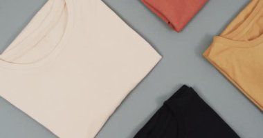 Gri arkaplanda fotokopi alanı olan düz tişörtlerin olduğu bir video. Moda, trendler ve giyim konsepti.