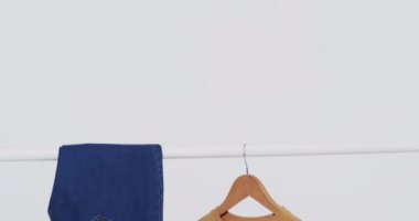 Askıda kot pantolon ve sarı tişört videosu ve beyaz arka planda kopya alanı. Moda, trendler ve giyim konsepti.