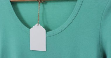 Üzerinde etiket olan yeşil tişörtün videosu ve beyaz arkaplanda kopyalama alanı. Moda, trendler ve giyim konsepti.
