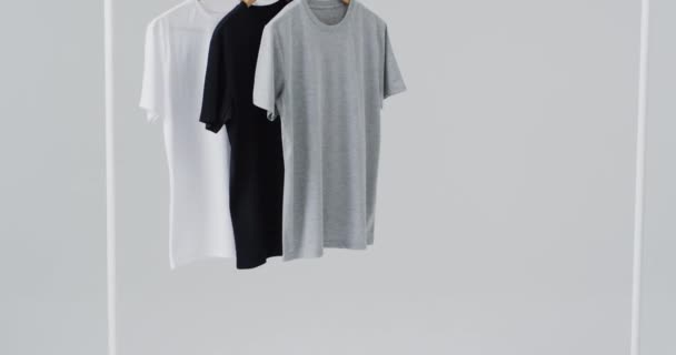 黑色T恤衫挂在衣架上的视频 并复制白色背景的空间 潮流和服装概念 — 图库视频影像