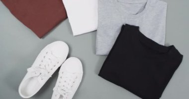 Gri arkaplanda fotokopi alanı olan düz tişörtlerin olduğu bir video. Moda, trendler ve giyim konsepti.