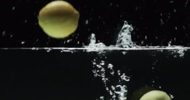 Siyah zemin üzerinde kopya alanı olan üç limonlu su altı videosu. Taze yiyecek, meyve ve renk kavramı.