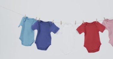 Çoklu renkli bebek videosu, beyaz arkaplanda fotokopi alanı olan askılardan sarkıyor. Bebek ve çocuklar moda, moda ve giyim konsepti.