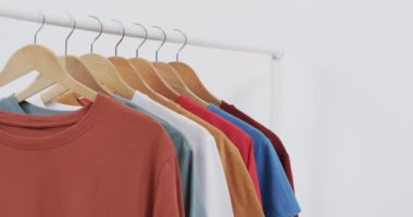 Askılarda çok renkli tişört seçimi ve beyaz arkaplanda kopya alanı. Moda, trendler ve giyim konsepti.