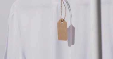 Beyaz arkaplanda etiket ve kopyalama alanı olan beyaz tişört videosu. Moda, trendler ve giyim konsepti.