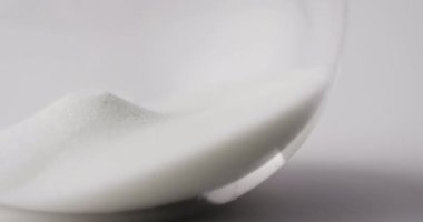 Kum saati üzerine kum dökülen yakın çekim videosu, beyaz arkaplanda kopyalama alanı. Zaman ve zaman tutma kavramı.