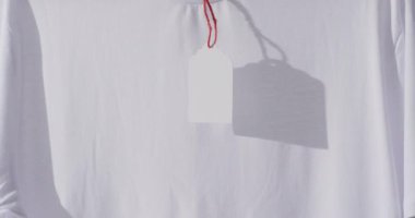 Beyaz arkaplanda etiket ve kopyalama alanı olan beyaz tişört videosu. Moda, trendler ve giyim konsepti.