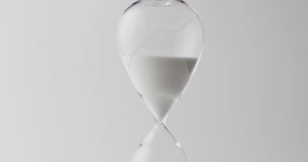 Video of hourglass with sand pouring, copy space on white background. Time and time keeping concept.