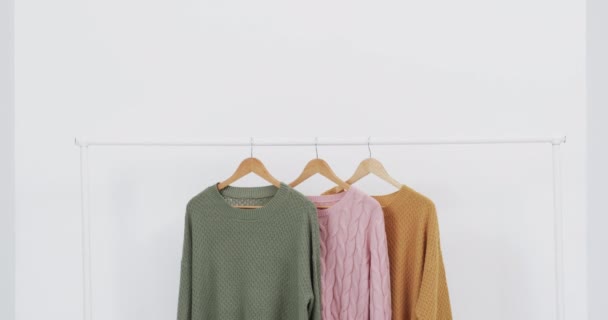 三款多色毛衣挂在衣架上的视频和白色背景的复制空间 潮流和服装概念 — 图库视频影像