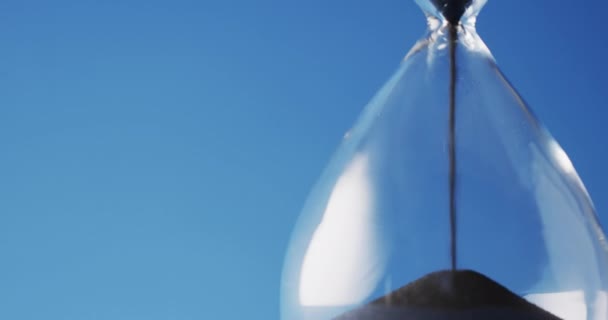 Video Close Hourglass Black Sand Pouring Copy Space Blue Background — Vídeos de Stock