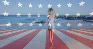 Sahilde denize doğru yürüyen mutlu beyaz kadın üzerine bayrak animajı. Dijital bileşim, çoklu pozlama, keyif, tatil, özgürlük ve vatanseverlik kavramı.