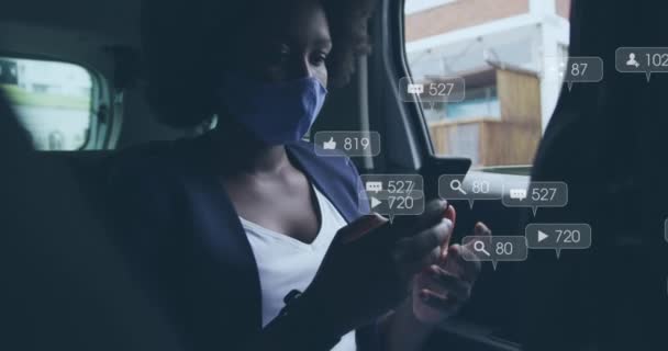 アフリカ系アメリカ人女性が車内でスマートフォンを使用してマスクを着用したソーシャルメディアアイコンのアニメーション ソーシャルメディアネットワーキングとコビド 19パンデミックコンセプト — ストック動画