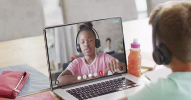 Bilgisayarında Afrikalı Amerikalı liseli kızdan öğrenen beyaz bir öğrenci. Eğitim, öğrenim ve çevrimiçi eğitim kavramı.