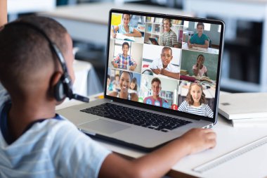Afro-Amerikalı bir çocuğun dizüstü bilgisayarında çeşitli öğrencilerle görüntülü bir görüşme yapması. Uzak öğrenim çevrimiçi eğitim kavramı