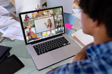 Çift ırklı bir çocuğun evdeki laptopta çeşitli öğrencilerle görüntülü bir görüşme yapması. Uzak öğrenim çevrimiçi eğitim kavramı