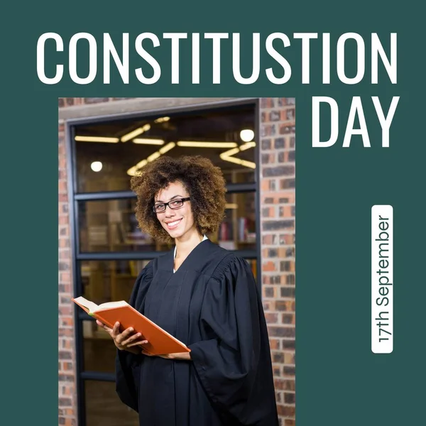 Constitution day text in white on green with happy biracial female attorney in gown with book. American constitution and federal government law celebration day digitally generated image.