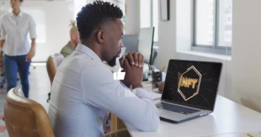 Dizüstü bilgisayardaki Nft metin ikonuna bakan Afro-Amerikan adamın başparmak kaldırma simgeleri. Dijital bileşik, çoklu pozlama, para birimi, bankacılık, sosyal medya ve teknoloji konsepti gibi..