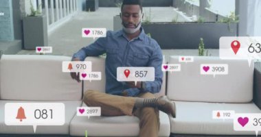 Sosyal medya simgelerinin evde akıllı telefon kullanan Afro-Amerikan bir adam üzerinde canlandırılması. Sosyal medya ağı ve covid-19 salgın konsepti