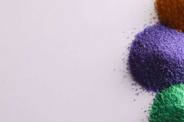 Çok renkli kum yığınlarını kapat ve beyaz arkaplanda kopyalama alanı oluştur. Kum, doku, hareket, şekil ve renk kavramı.