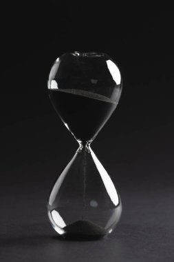 Kum saatini siyah kumla kapat ve siyah arkaplana kopyala. Zaman, zaman tutma, şekil ve renk kavramı.