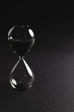 Kum saatini siyah kumla kapat ve siyah arkaplana kopyala. Zaman, zaman tutma, şekil ve renk kavramı.