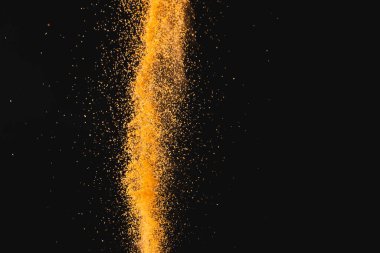 Havaya atılan turuncu kumu kapat ve siyah arkaplana kopyala. Kum, doku, hareket, şekil ve renk kavramı.