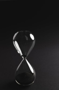 Kum saatini siyah kumla kapat ve siyah arkaplana kopyala. Zaman, zaman tutma, şekil ve renk kavramı.