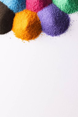 Çok renkli kum yığınlarını kapat ve beyaz arkaplanda kopyalama alanı oluştur. Kum, doku, hareket, şekil ve renk kavramı.