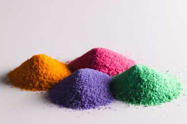 Çok renkli kum yığınlarını kapat ve beyaz arkaplanda kopyalama alanı oluştur. Kum, doku, hareket, şekil ve renk kavramı.