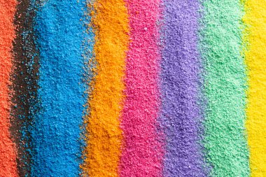 Gökkuşağı renkli kum ve fotokopi alanı arkaplanının şeritlerini kapatın. Kum, doku, hareket, şekil ve renk kavramı.