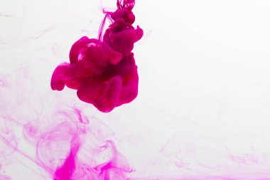 Sudaki pembe mürekkebi kapatın ve beyaz arkaplanda kopya alanı olsun. Mürekkep, sıvı, şekil ve renk kavramı.