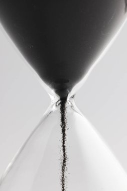 Kum saatini siyah kumla kapat ve beyaz arkaplana kopyala. Zaman, zaman tutma, şekil ve renk kavramı.